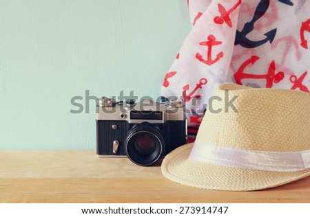 fedora hat, old vintage camera and scarf over wooden table. relaxation or vacation concept