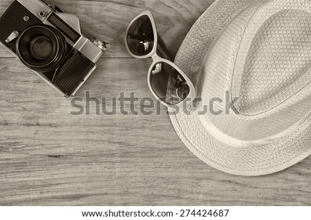 top view of stylish hat woman sunglasses old camera over wooden table. black and white photo. vacation and travel concept