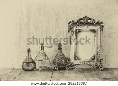 image of victorian vintage antique classical frame, jewelry and perfume bottles on wooden table. old style photo