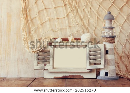 old vintage wooden white frame and lighthouse on wooden table. vintage filtered image. nautical lifestyle concept