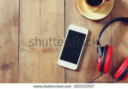 top view image of smartphone with blank screen headphones and coffee cup. room for text