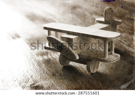 wooden airplane toy over textured wooden background. retro style image.  black and white old style photo