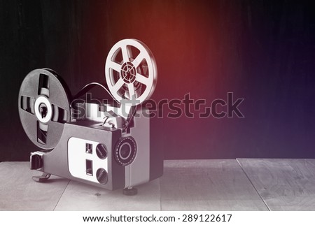 old 8mm Film Projector over wooden table and textured background