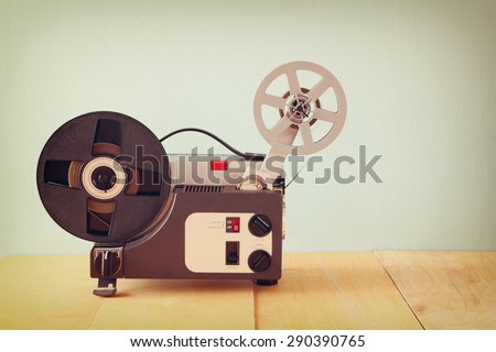 old 8mm Film Projector over wooden table and textured background