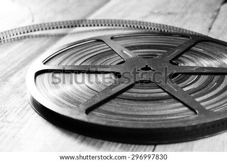 close up  image of old 8 mm movie reel over wooden background. black and white photo