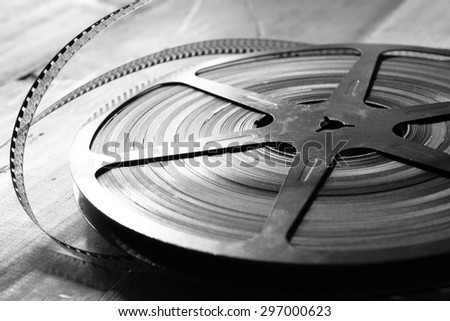 close up  image of old 8 mm movie reel over wooden background. black and white photo