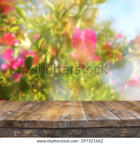 wood board table in front of summer landscape with double exposure of flower bloom