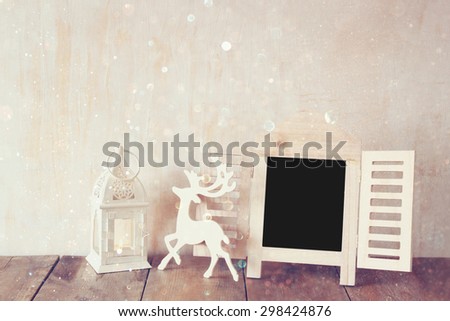 abstract filtered photo of decorative chalkboard frame and wooden deer over wooden table. ready for text or mockup.  retro filtered image with glitter overlay