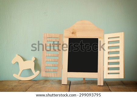 image of vintage wooden classical frame and wooden rocking horse on wooden table. filtered image