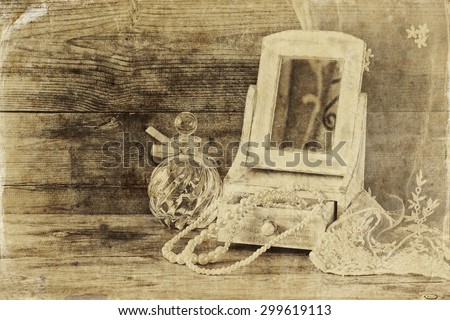 vintage pearls , antique wooden jewelry box with mirror and perfume bottle on wooden table. black and white style photo