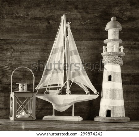 old vintage lighthouse, sailing boat  and lantern on wooden table. vintage filtered image. black and white photo