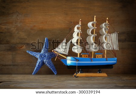 old vintage wooden sailing boat ans starfish on wooden table. vintage filtered image. nautical lifestyle concept