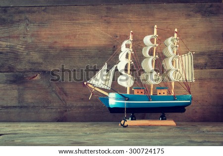 old vintage wooden white sailing boat on wooden table. vintage filtered image. nautical lifestyle concept