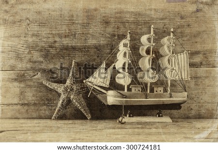 old vintage wooden sailing boat ans starfish on wooden table. vintage filtered image. nautical lifestyle concept. black and white