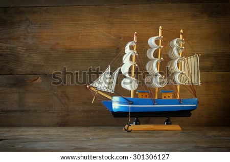 old vintage wooden white sailing boat on wooden table. vintage filtered image. nautical lifestyle concept