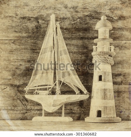 old vintage wooden lighthouse and sailing boat on wooden table. old style black and white photo. nautical lifestyle concept
