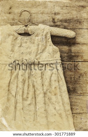vintage cream girl\'s dress on hanger with on wooden background. black and white old style photo