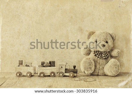Wooden toy train and teddy bear over wooden floor. black and white style photo