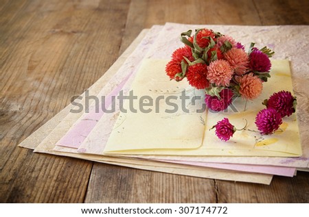 selective focus image of dry flowers and hand made vintage letters paper on wooden table. retro filtered image