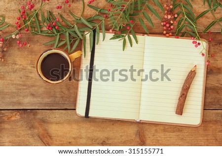 blank open  vintage notebook, old paper and wooden pencil next to cup of coffee over wooden table. ready for mockup