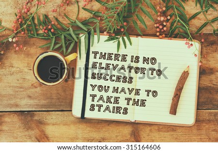 success and inspiration phrase. open notebook with text next to cup of coffee over wooden table. filtered image, faded style