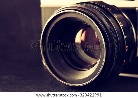 close up photo of old camera lens over wooden table. image is retro filtered. selective focus