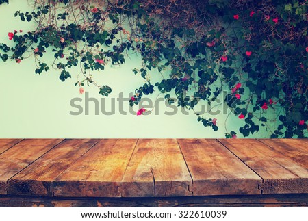 vintage wooden board table in front of climbing plant against the wall
