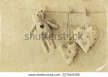 teddy bear and fabric hearts hanging on rope. retro filtered image. old style photo