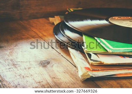 records stack with record on top over wooden table. vintage filtered