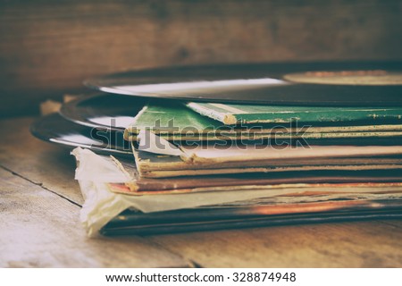 selective focus image of records stack with record on top over wooden table. vintage filtered