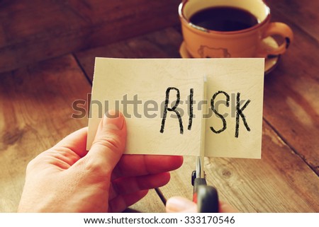 man hand holding scissors and cutting paper card with the word risk .