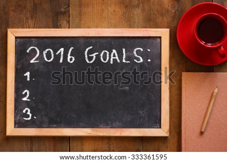 top view of blackboard with the phrase 2016 goals over wooden board with coffee and notebook