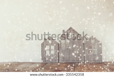 high key image of vintage wooden house decor on wooden table. retro filtered. selective focus. snow overlay