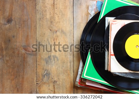records stack with record on top over wooden table. vintage filtered