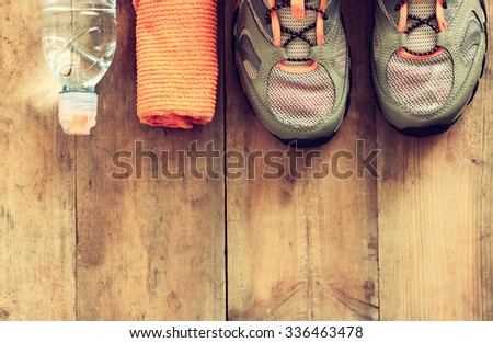 fitness concept with towel, towel and sport footwear over wooden background. retro filtered