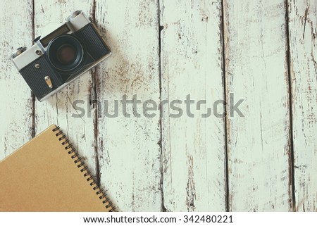top view image of blank notebook and old camera.  retro filtered image