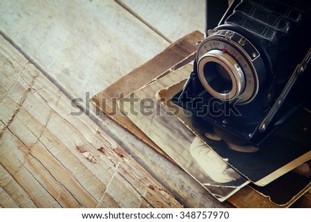 old photo camera, antique photos on wooden table. retro filtered image. selective focus