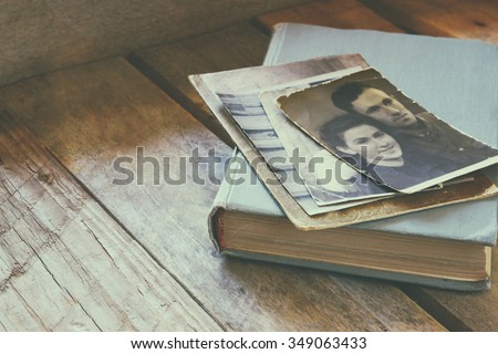 antique photos and old book on wooden table. retro filtered image. selective focus