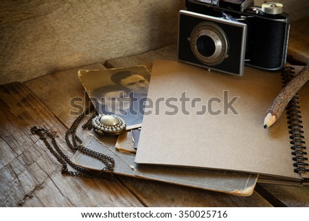 old photo camera, open notebook and antique photos on wooden table. retro filtered image