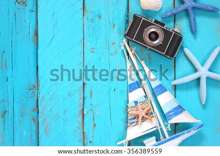 top view image of photo camera, wood boat, sea shells and star fish over wooden table