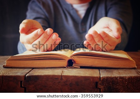 low key image of person sitting next to prayer book