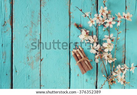 image of spring white cherry blossoms tree next to wooden colorful pencils on blue wooden table. vintage filtered image