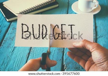 man hand holding card with the word budget. cutting budget and costs concept. retro style image