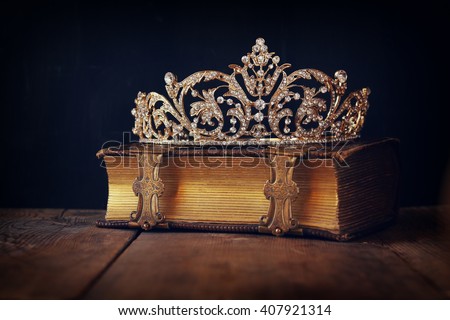 low key image of beautiful diamond queen crown on old book. vintage filtered. selective focus. medieval period concept