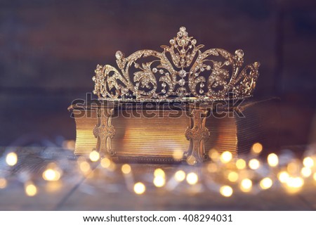 low key image of beautiful diamond queen crown on old book. vintage filtered with glitter overlay. selective focus. medieval period concept