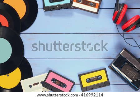 top view image of cassette, headphones, records and old tape player over wooden background. vintage filter