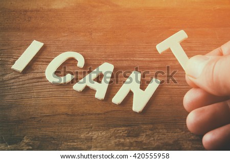 man hand spelling the word I CAN\'T from wooden letters, cutting the letter T so it written I CAN. success and challenge concept. retro style image