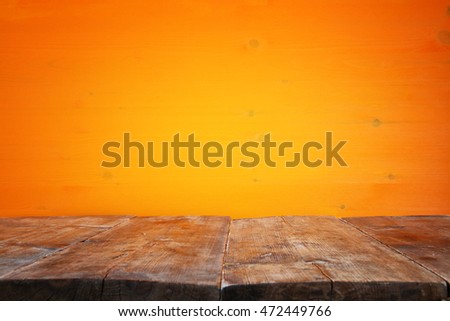 Halloween holiday concept. Empty rustic table in front of orange wooden background. Ready for product display montage