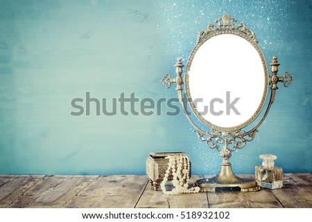 Old vintage oval mirror and woman toilet fashion objects on wooden table. Filtered image