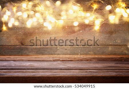 empty table in front of Christmas warm gold garland lights on wooden rustic background. selective focus